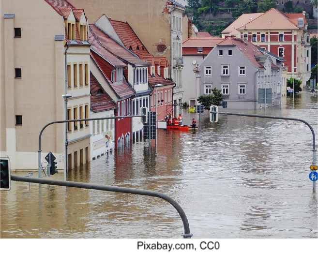 A flooded street with buildings partially submerged and a rescue boat.